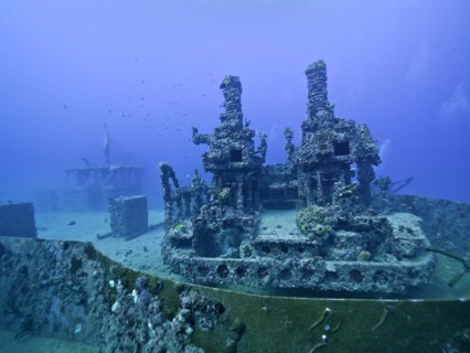 A complex underwater structure reclaimed by nature with visible coral growth: Wreck of the USS