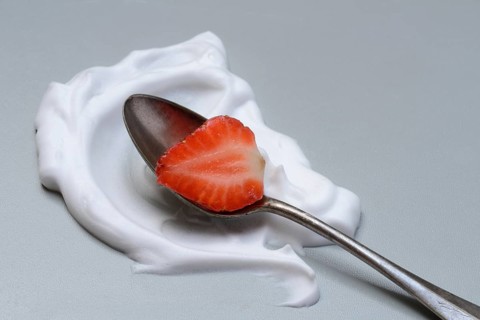 Strawberry with cream on a spoon