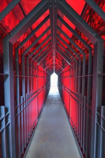 A long tunnel with red lighting and metallic structures conveys a futuristic and industrial