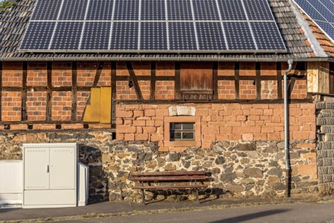Historic farmhouse with photovoltaic system, solar panels on the roof, house wall with differently