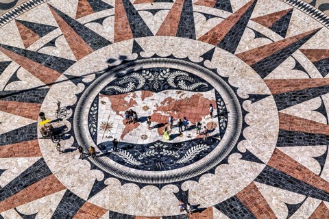 Ein Bodenmosaik mit einer Kompassrose und einer Weltkarte, umgeben von Menschenfiguren, die