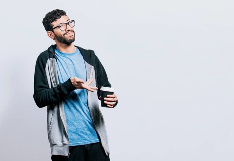 Smiling man showing coffee on isolated background. Guy pointing disposable cup of coffee isolated