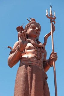 Photo from street level upward view of larger-than-life figure of god deity of Hindi Hindu statue
