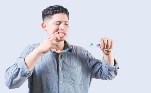 Man suffering from gum pain holding toothbrush. People holding toothbrush with gum problem. Person