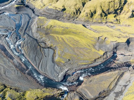 River along road F232 Öldufellsleid, slopes of Mt. Öldufell, moss-covered hill in black lava sand,