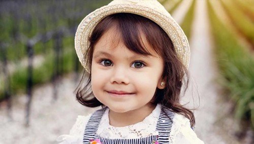Girl with hat and striped shirt smiles on a path into the camera, AI generated, AI generated