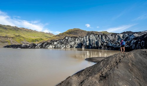 Tourist on the shore of a glacier lagoon, glacier tongue and lake, Sólheimajökull, South Iceland,