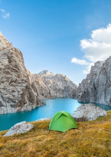 Green tent at the turquoise mountain lake Kol Suu with rocky steep mountains, Kol Suu Lake, Sary