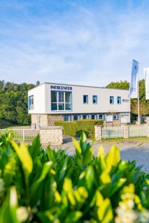 Modern information centre building with large glass windows and fences, surrounded by green nature,