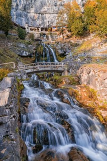 Impressive waterfall flowing over a rocky stream under a bridge, St. Beatus Caves, Switzerland,