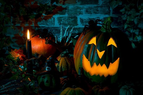 Illuminated pumpkin with spiders and candle in a mystical Halloween scene