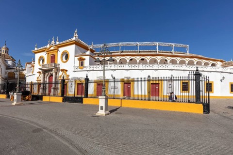 Round bullring with yellow and white details under a clear sky, Seville