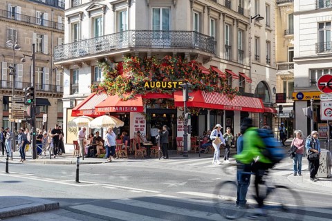 Snapshot of a lively street café with lush flower arrangements and cyclists, Paris