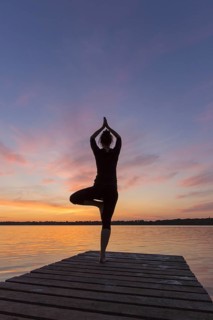 Woman practicing standing posture Vrikshasana, Tree Pose, one legged balancing asana of the