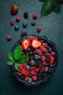 Mix of fresh berries, in a basket, on a wooden gray table, no people, top view