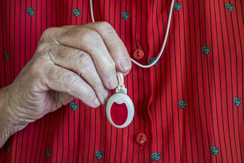 Close up of hand holding life-saving personal alarm for the elderly and disabled people showing