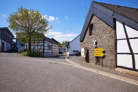 Street with half-timbered houses, sandstone buildings and signposts to Bad Münstereifel and