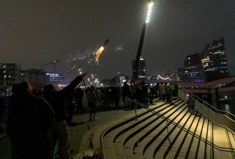 Person launches firework rocket from his hand, New Year's Eve 2025 on the Elbe promenade in
