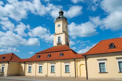 Historic building with clock tower and red roof tiles under a clear sky, town hall, museum,