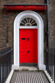 Red entrance door in a brick building with a cast-iron fence, Charles Dickens Museum, 48-49 Doughty