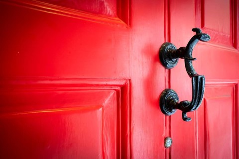 Close-up of a black door knocker on a red door, entrance to the Charles Dickens Museum, 48-49