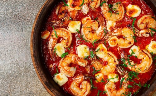 Saganaki with shrimp, in a clay pan, Greek dish, shrimp in tomato sauce, feta cheese, homemade, no