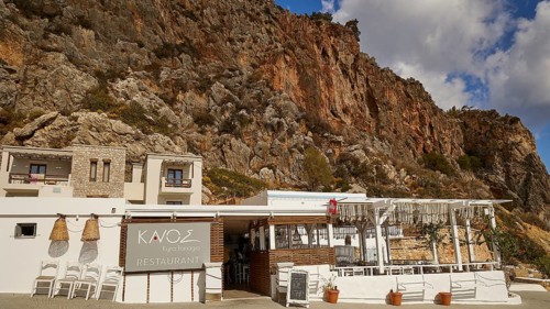 A restaurant in front of striking rocky cliffs with traditional stone architecture and wooden