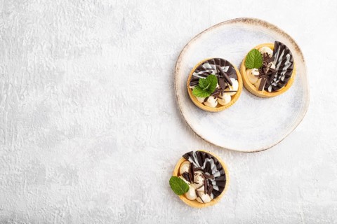 Sweet tartlets with chocolate and cheese cream on a gray concrete background. top view, flat lay,