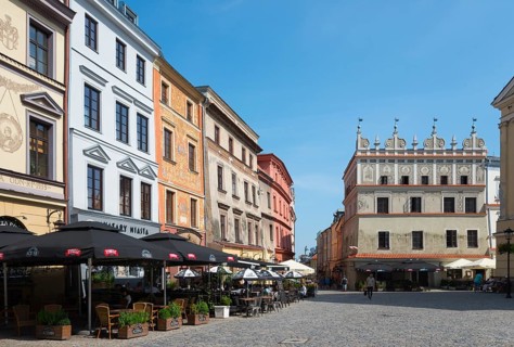 Town square with historic facades and street cafés under a blue sky, Chociszewska tenement house,