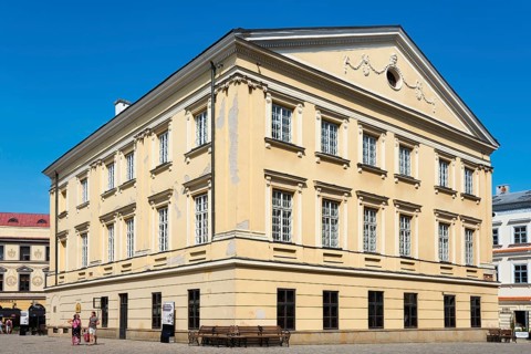 Historic yellow building with classical elements and rows of windows under a clear sky, registry
