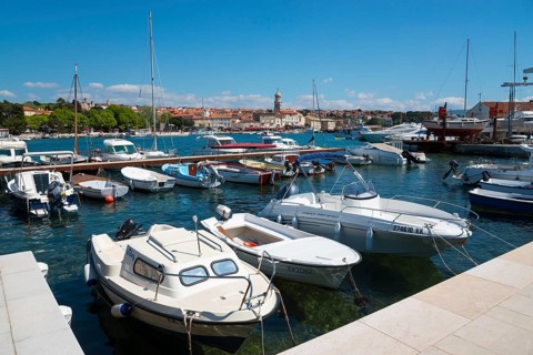 A busy harbour full of boats and yachts under a bright blue sky with a city view, Old Town, Krk