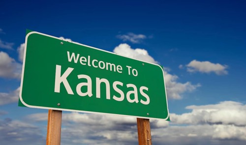 Welcome to kansas green road sign over blue sky with some clouds