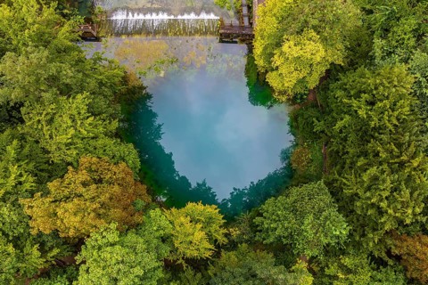 Blautopf Blaubeuren, source of the River Blau in a landscape with forest. Karst spring, geotope and