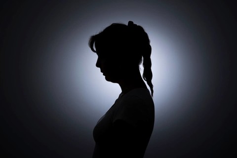Symbolic photo on the subject of loneliness in woman. The silhouette of a young woman stands out