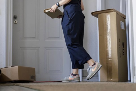 A woman leaves a parcel on her neighbour's doorstep in Berlin, 08.08.2024