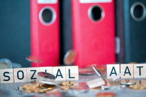 Wooden letters show the word SOCIAL STATE, falling coins knock over the letters (symbolic image)