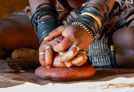 Hands of a woman with painting stone, Traditional Himba woman makes ochre colour for body painting