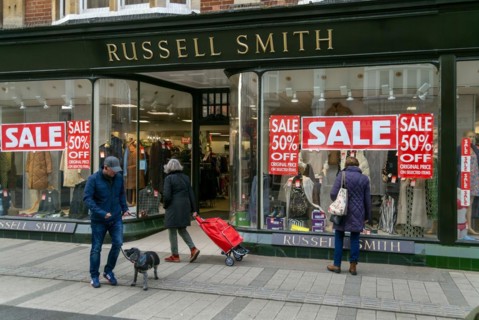 Sale poster signs in shop window of Russell Smith clothing store, Felixstowe, Suffolk, England, UK