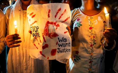 Students holds candle and shout slogans as they participate in a protest against the rape and