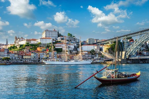 View of Porto city and Douro river with traditional boats with port wine barrels and sailing ship