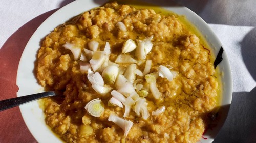 Fava, A plate of a traditional dish, chunky and garnished with onions, served on white crockery,
