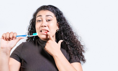Young woman with gingivitis holding toothbrush isolated. Girl suffering from gum pain holding