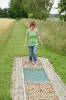 Woman walking barefoot over glass gravel and bottle corks, barefoot path Tilbeck Abbey, Havixbeck,