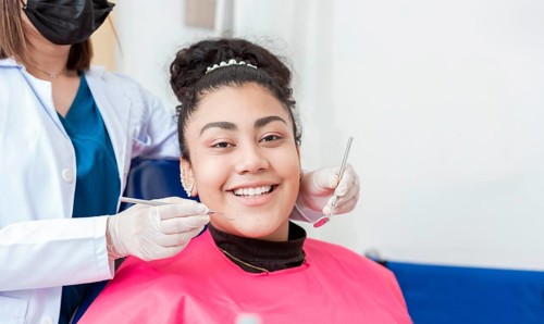 Dentist doctor examining mouth to female patient looking at camera. Dentist with probe and dental