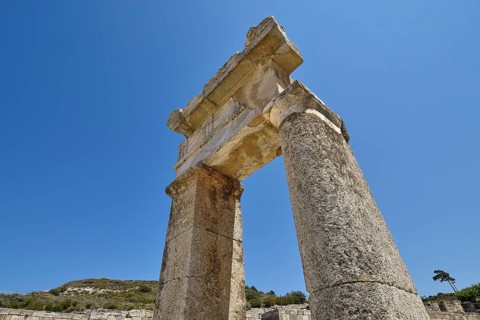 Stone ancient column rises under a clear blue sky, Kamiros, Archaeological site, Ancient city,