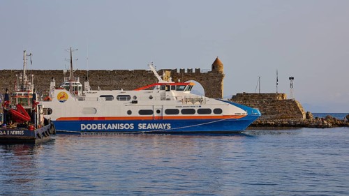 A white ferry lies in front of an old coastal fortification in the calm sea, De Naillac Tower,