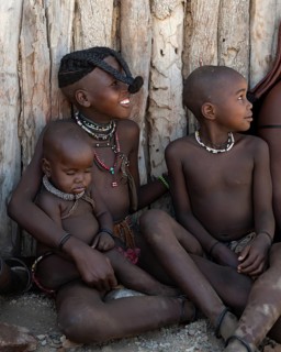 Himba boy and Himba girl with forward braided plaits with baby, near Opuwo, Kaokoveld, Kunene,
