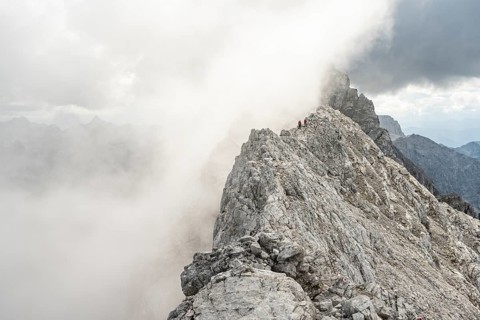 Clouds move around narrow rocky mountain ridge with mountaineers, Watzmann crossing to Watzmann
