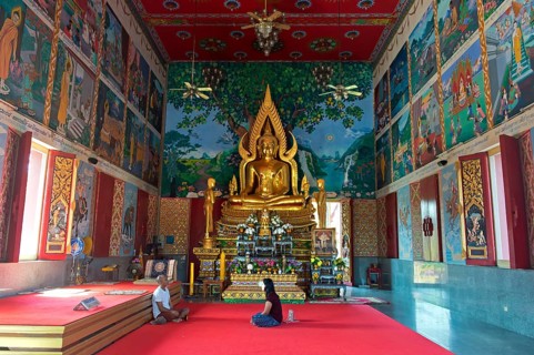 Man and woman sitting in dialogue in a prayer hall in the Buddhist temple Wat Plai Laem, Koh Samui,