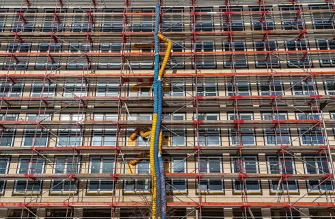 Large construction site, scaffolded shell of an office building complex, air hoses for building